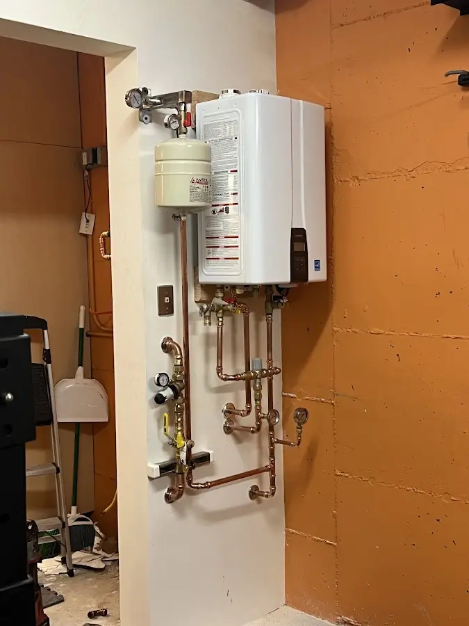 Plumbing technician inspecting water heater connections in Brighton